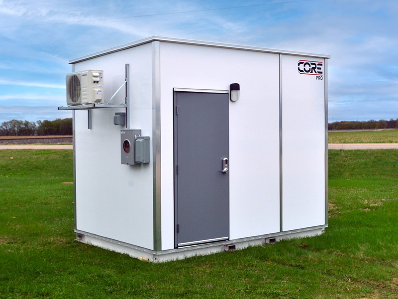 8ft-by-12ft-shelter-mobile Exterior view of a CORPRO prefabricated telecommunications shelter featuring a secure steel access door, integrated HVAC climate-control system, and utility service connections, designed to protect critical fiber optic, broadband, wireless, and network infrastructure equipment in outdoor environments.
